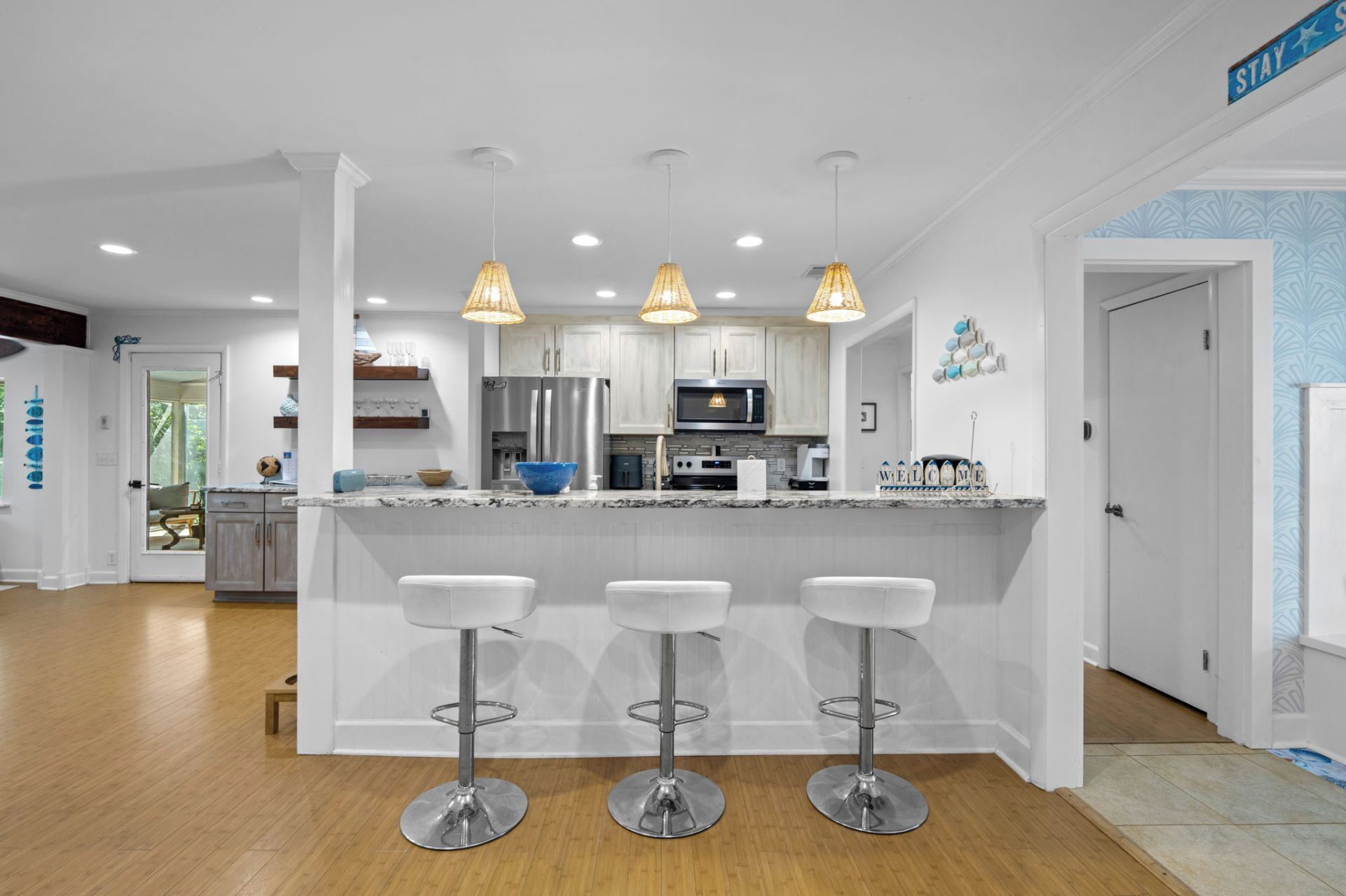 A modern kitchen with white cabinets, stainless steel appliances, and a central island with bar stools.