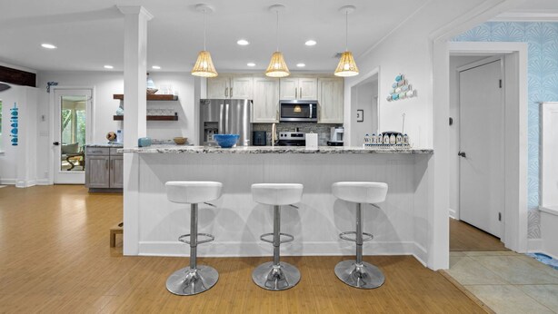 Una cocina moderna con armarios blancos, electrodomésticos de acero inoxidable y una isla central con taburetes de bar.