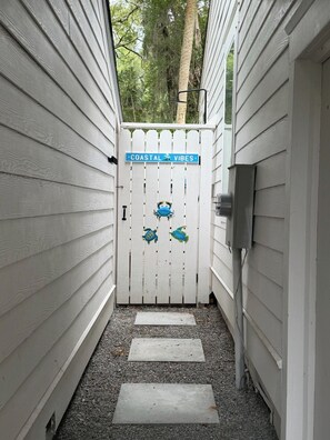 A narrow pathway leading to a white gate with a sign reading 'COASTAL VIBES.' - Classic Beach Home, Golf Cart Included - 703 Skip Jack (Fripp Island)