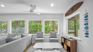 Una sala de estar moderna con un sofá, sillas, una mesa y una estantería.