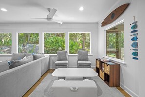Ein modernes Wohnzimmer mit einer Couch, Sesseln, einem Tisch und einem Bücherregal.