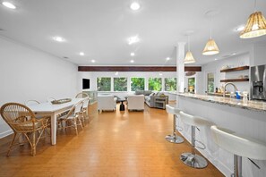Eine moderne Küche mit Barbereich, Holzboden und großen Fenstern.