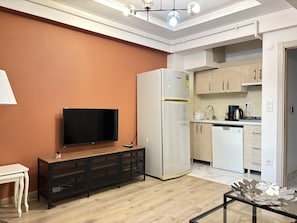 Ein modernes Wohnzimmer mit Flachbildfernseher, einer schwarzen Konsolentisch und einem dekorativen Glastisch.
