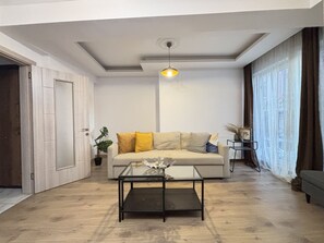 A modern living room with a sofa, a coffee table, and a pendant light. - Family-Friendly 2BR • Central Taksim (Istanbul)