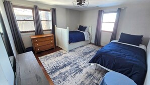 A bedroom with a bed, dresser, and a window with curtains. - Best Views of Webster Lake! Paddleboards + Swimming (North Webster)