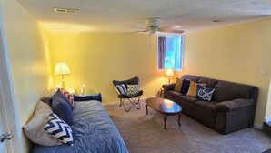 A compact living space with a bed, a sofa, a small table, and a ceiling fan. - Best Views of Webster Lake! Paddleboards + Swimming (North Webster)