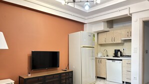En moderne stue med et fladskærms-tv, et sort konsolbord og et dekorativt sofabord i glas.