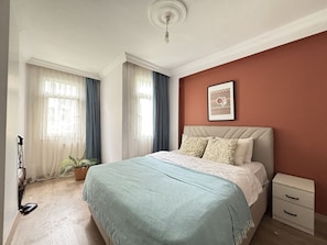 Ein Schlafzimmer mit einem Bett, einem Nachttisch, einem Wandbild und einer Topfpflanze.