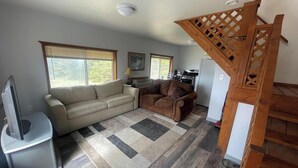 Una sala de estar con un sofá, un televisor, una chimenea y una escalera.