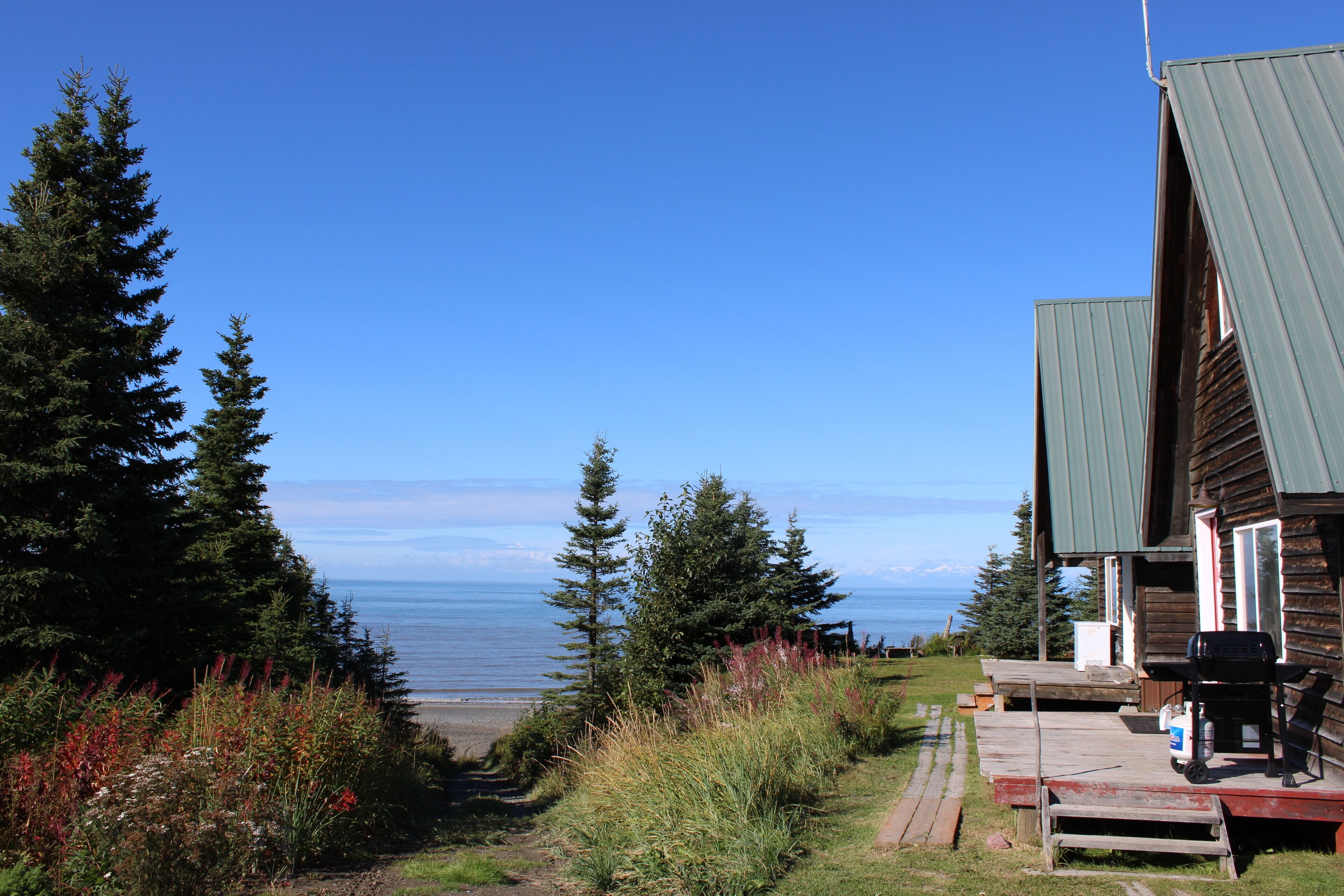 A cabin with a deck, overlooking a beach and the ocean.