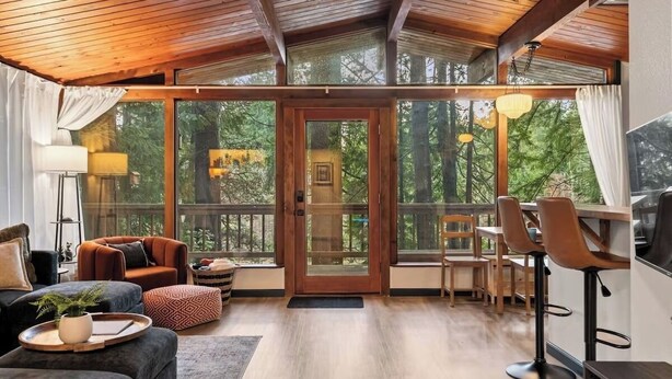 A spacious living area with a wooden ceiling, large windows, and a dining area with bar stools.