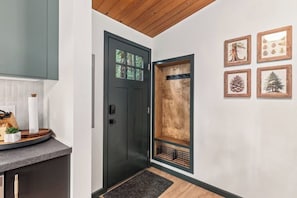 Una cocina moderna con una puerta oscura, techo de madera y un estante con marcos.