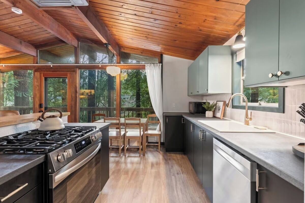 Une cuisine moderne équipée d’une cuisinière à gaz, de chaises en bois et offrant une vue sur l’extérieur.