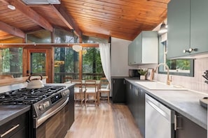 Una cocina moderna con estufa a gas, sillas de madera y vistas al exterior.