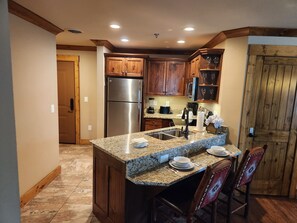 Eine Küche mit Granit-Arbeitsplatten, Holzschränken, einem Edelstahl-Kühlschrank und einem Essbereich mit Stühlen und Tisch.