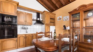 A kitchen with wooden cabinets, a black oven, and a dining table with chairs. - Home2Book La Molina C, Rural Retreat (Antigua)