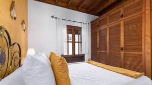 A bedroom with a bed, wooden wardrobe, and a window with curtains. - Home2Book La Molina C, Rural Retreat (Antigua)