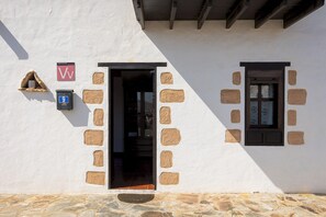 Un bâtiment doté d’une façade en pierre, d’une porte et d’une fenêtre.