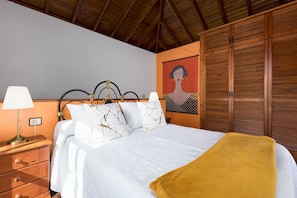 Ein Schlafzimmer mit einem Bett, Nachttischen, einem hölzernen Kopfteil, einem Gemälde und einem Kleiderschrank.