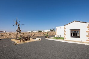 Un bâtiment blanc avec une fenêtre, un moulin à vent et un espace aménagé avec des sièges.