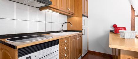 Een keuken met houten kastjes, een roestvrijstalen spoelbak en een inbouwoven.