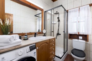 Een badkamer met een douche, toilet, wastafel en een wasmachine.