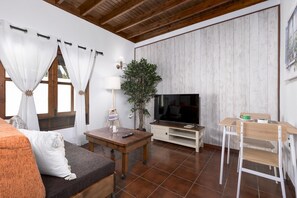 Un salon avec un canapé, un téléviseur, une table en bois et une plante.