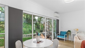 A modern living room with a round table, two chairs, a sofa, and a staircase leading to an outdoor area. - 2BR 2BA Indooroopilly | Walk to Shops & Bus (Indooroopilly)