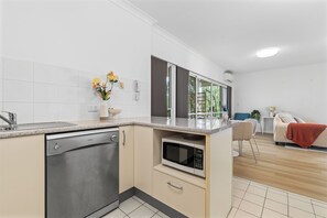 Eine moderne Küche mit Geschirrspüler, Mikrowelle und einer kleinen Essecke mit Stuhl und Tisch.