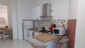 Una cuina amb taulell de fusta, fogó de gas, microones i nevera.
