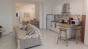 Una cuina moderna amb microones, fogó i zona de menjador amb taula i cadires.