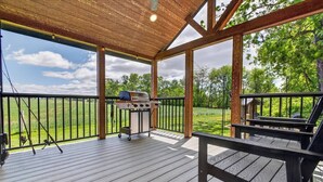 Eine Außenterrasse mit Grill, Holzgeländern und Blick auf die umliegende Landschaft.