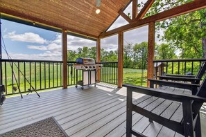 An outdoor deck with a grill, wooden railings, and a view of the surrounding landscape. - Private Tiny Home Surrounded By Farmland W/Hottub (Gordonville)