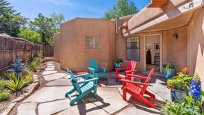 Un patio con sillas Adirondack, un sendero de piedra y plantas en macetas.