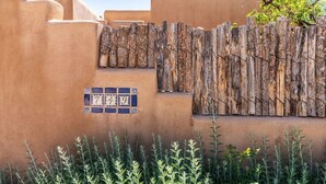 Un edificio con fachada de estuco, una valla de madera y una placa con un número.