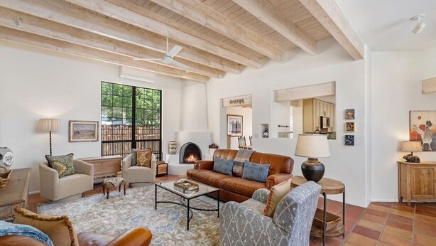 Un salón espacioso con chimenea, vigas de madera y un ventanal grande.