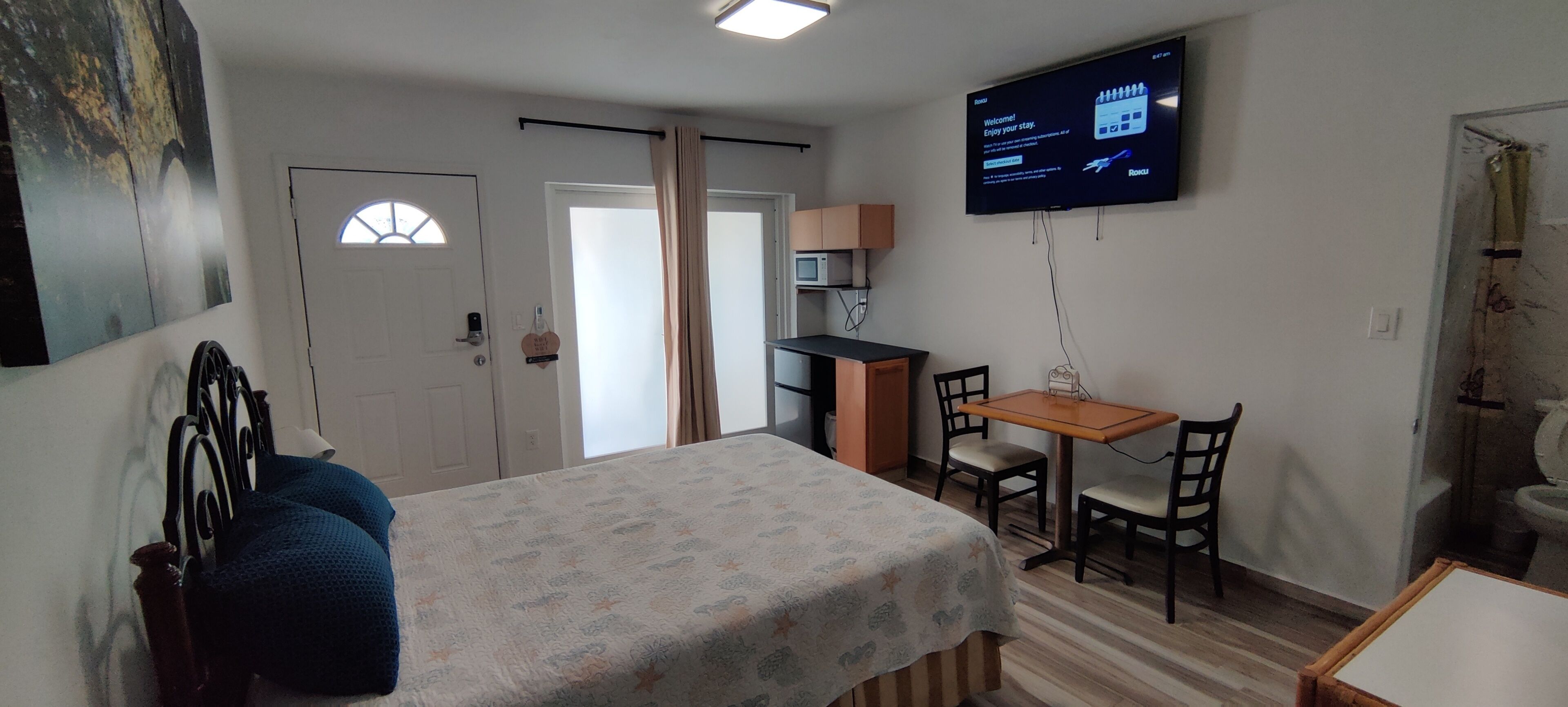 Une pièce comprenant un lit, un bureau, une chaise, un téléviseur et une porte.