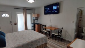 Une pièce comprenant un lit, un bureau, une chaise, un téléviseur et une porte.
