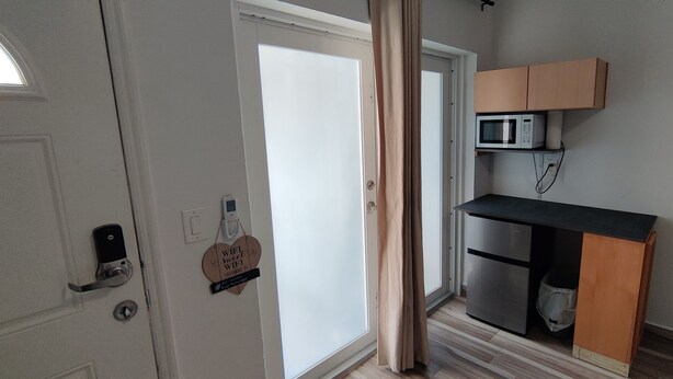 Une cuisine compacte équipée d’un four à micro-ondes, d’un réfrigérateur et d’un meuble en bois.