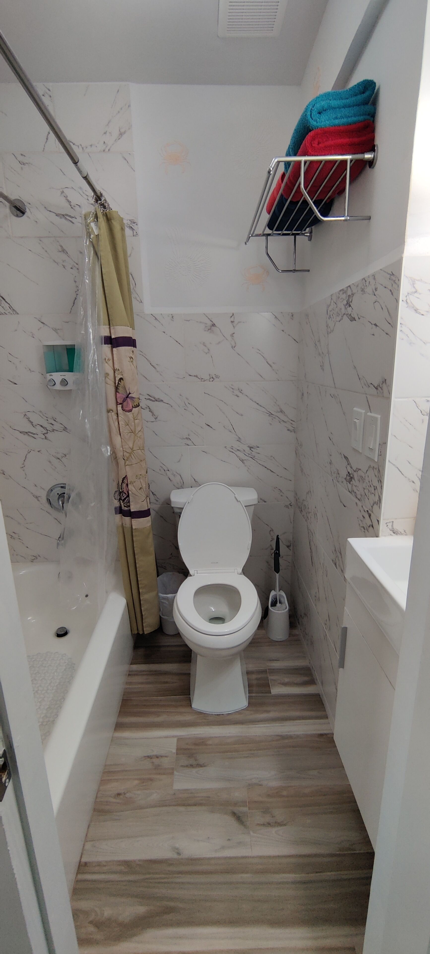 Ein Badezimmer mit Toilette, Dusche und Handtuchhalter mit Handtüchern.