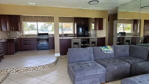 Una cocina moderna con armarios oscuros, una isla central y una zona de comedor con un sofá gris.