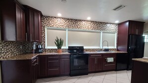 Una cocina con armarios de madera oscura, un salpicadero de azulejos, una estufa negra y un refrigerador negro.