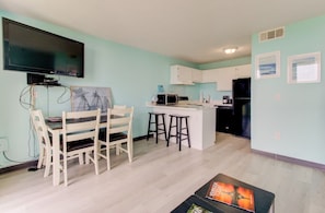 Una cocina moderna con armarios blancos, un refrigerador negro y una zona de comedor con una mesa y sillas.