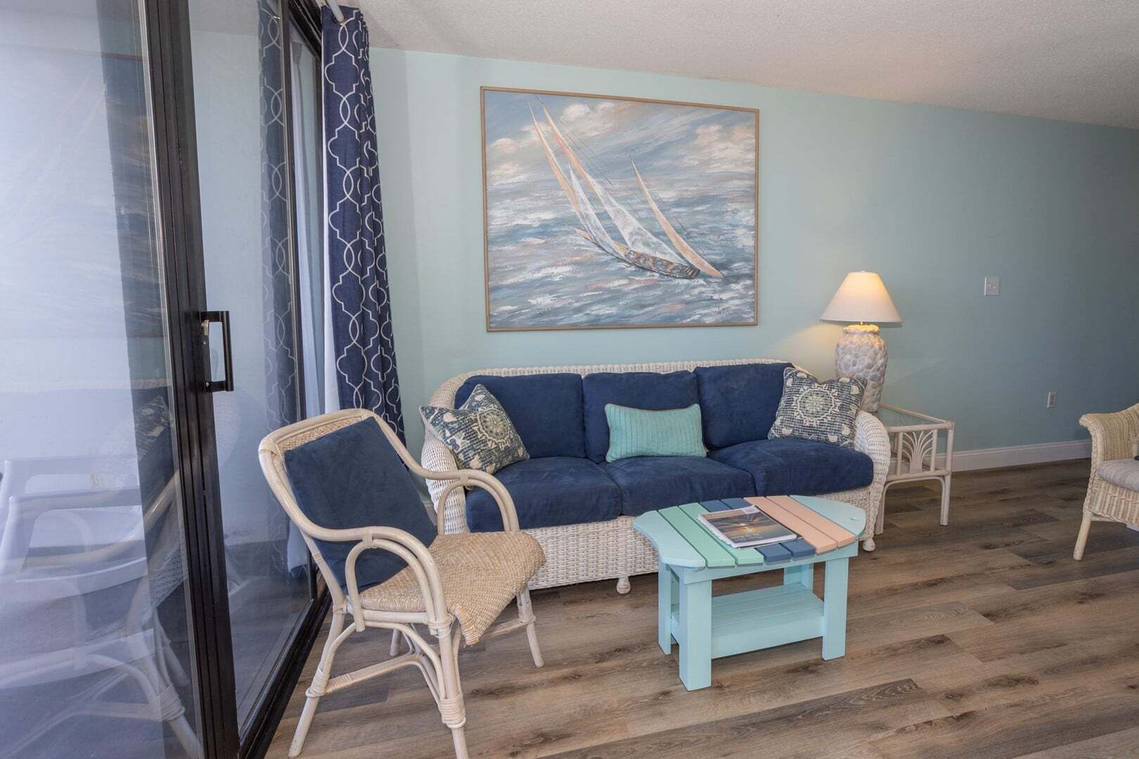 Una sala de estar con un sofá, dos sillones, una mesa de centro y un cuadro de un velero en la pared.