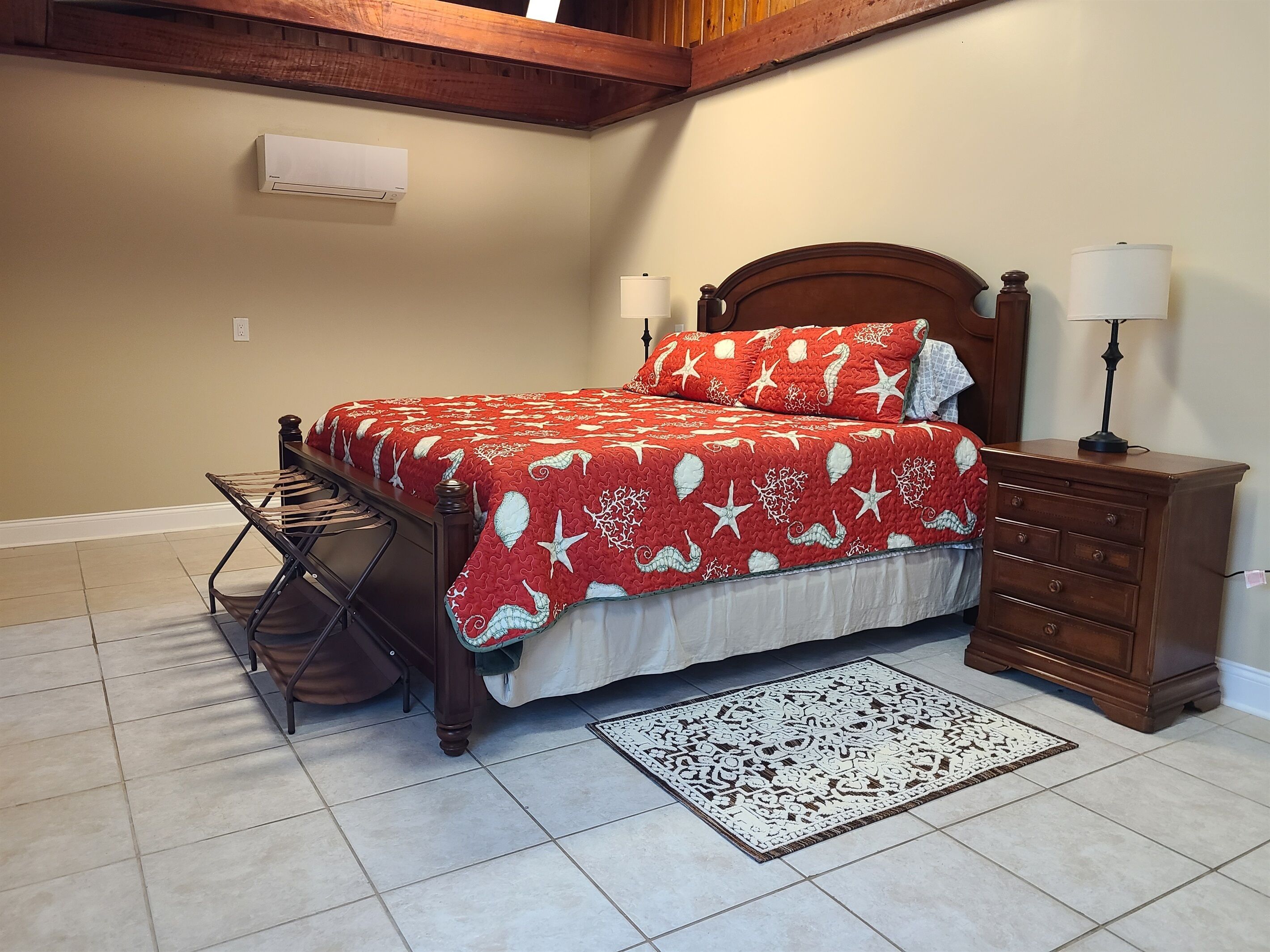 Ein Schlafzimmer mit Bett, Schminktisch, Lampe, Teppich und Deckenventilator.
