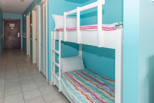 A bunk bed room with a tiled floor and teal walls.