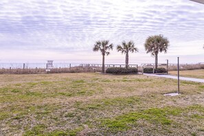 A beach area with a wooden boardwalk, palm trees, and a lifeguard tower.