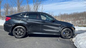 A black car parked on a road with snow on the sides.