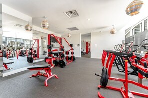 A gym with red equipment, mirrors, and a view of the outside.