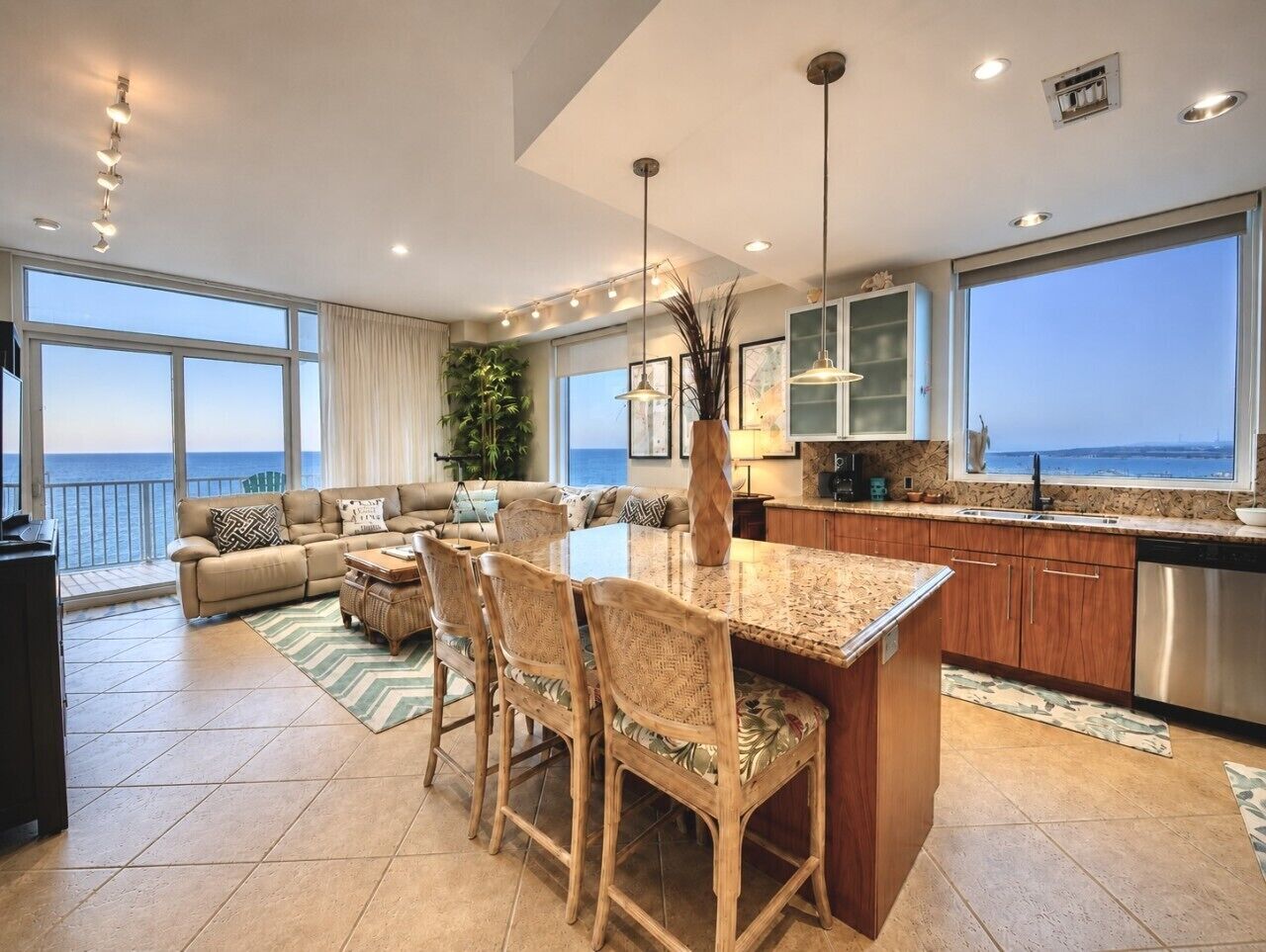 Un vaste espace de vie avec une grande fenêtre donnant sur la mer, un coin repas avec une cuisine en arrière-plan et un coin salon confortable avec vue.